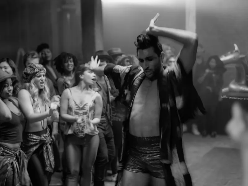 Dancer in an open robe and shorts posing mid-move in front of a cheering crowd, for Caught a Ghost’s “Get Your Life”