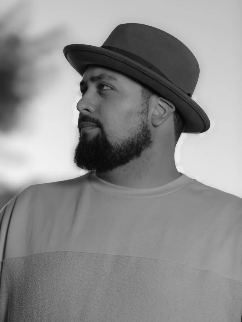 Marvin Lemus in a hat, looking off to the side