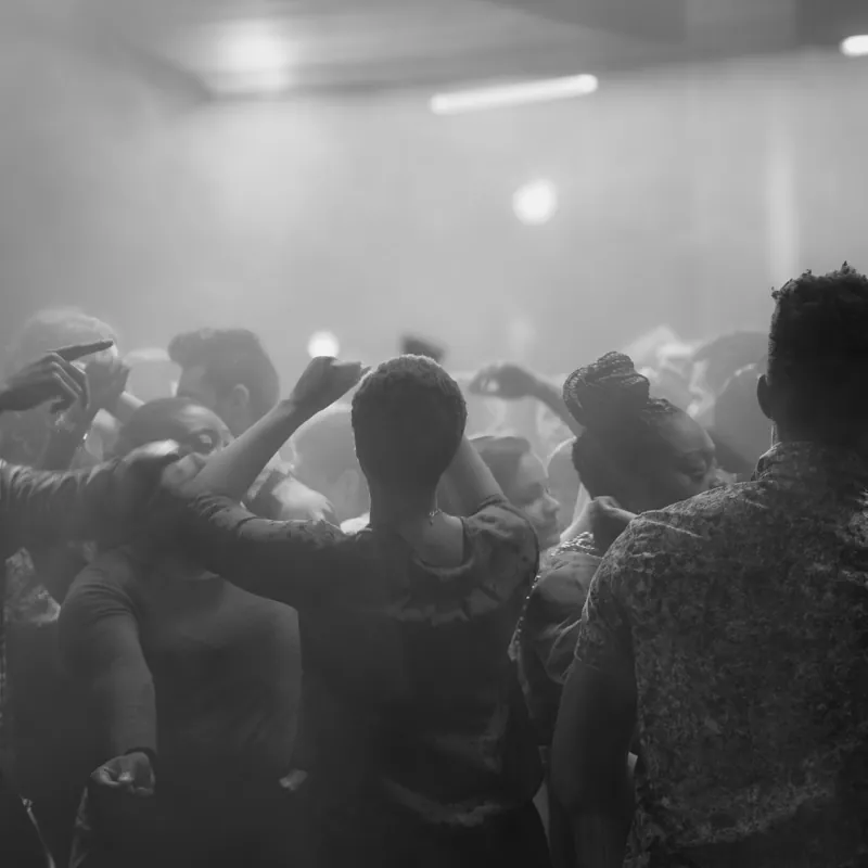 Crowd dancing with raised arms on a hazy dance floor